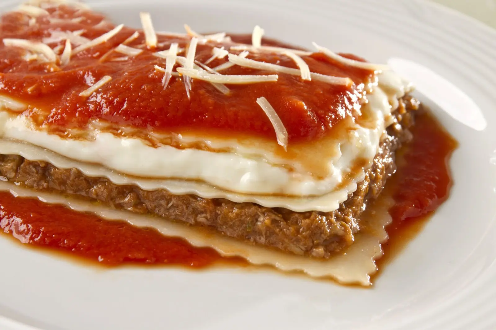 Fatia de lasanha à bolonhesa com camadas aparentes, pomodoro e parmesão